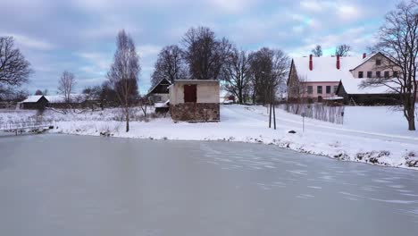 town buildings near small park and frozen lake, aerial ascending view