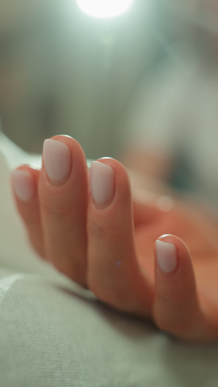 closeup hand with manicure resting on treatment table, microcurrent gel applied at fingertip, subtle electrode glint under soft clinical lamp, shallow depth of field and serene sterile spa atmosphere
