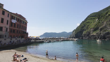 people on vacation at cinque terre coast on a sunny day in vernazza village, italy. panning shot