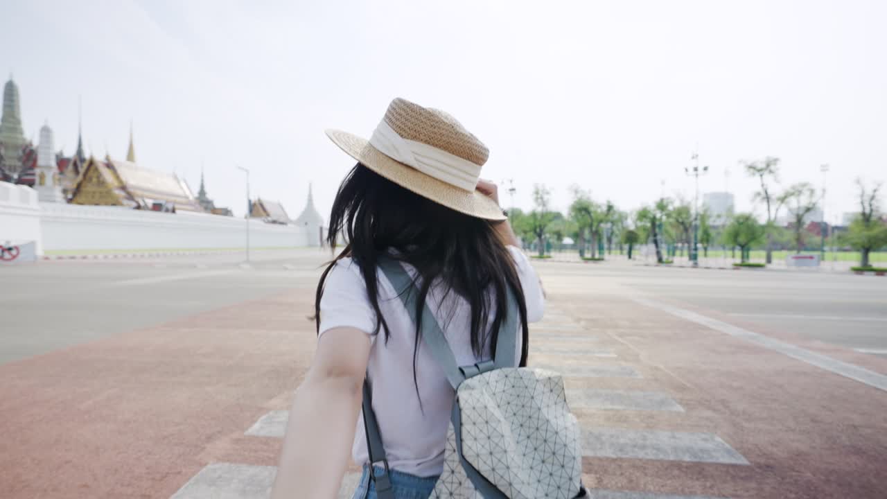 joven asiática alegre sosteniendo la mano de su novio cruzando la carretera en bangkok