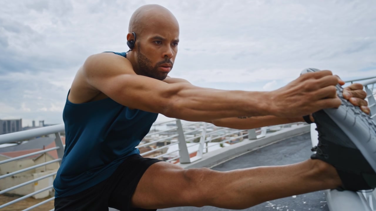 Athletic Man Stretching Legs on Urban Pedestrian Bridge