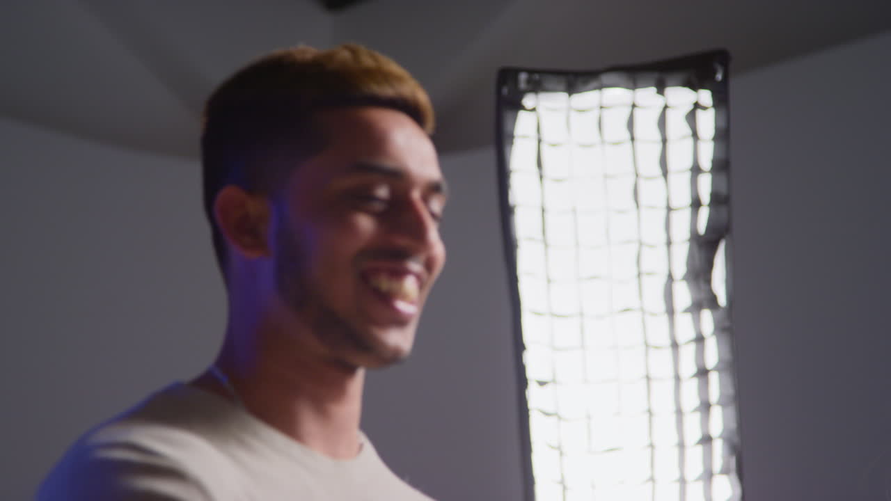 한 젊은이가 스튜디오 사진 촬영에서 미소 짓고 엄지손가락을 들어 올립니다.