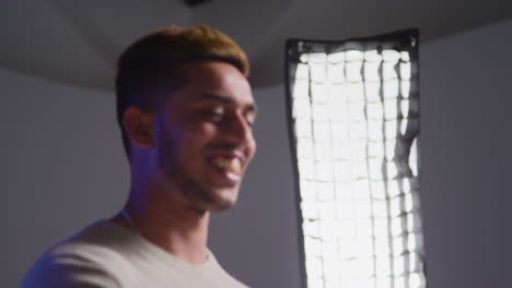 A young man smiles and gives a thumbs up in a studio photo shoot.