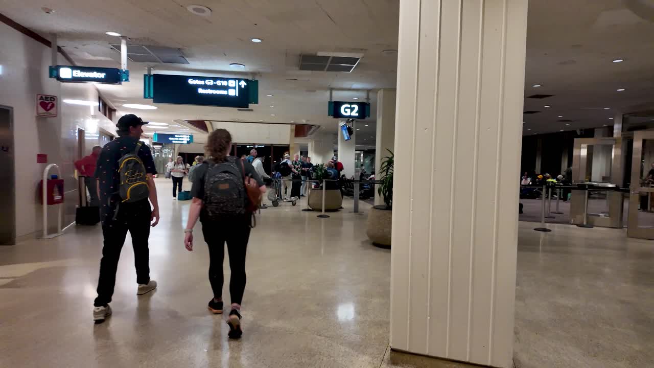 Passengers couple Walking to terminal and gates at Daniel K. Inouye International Airport in Honolulu, Hawaii, USA. Traveling concept. Happy loving couple walking inside of airport terminal.