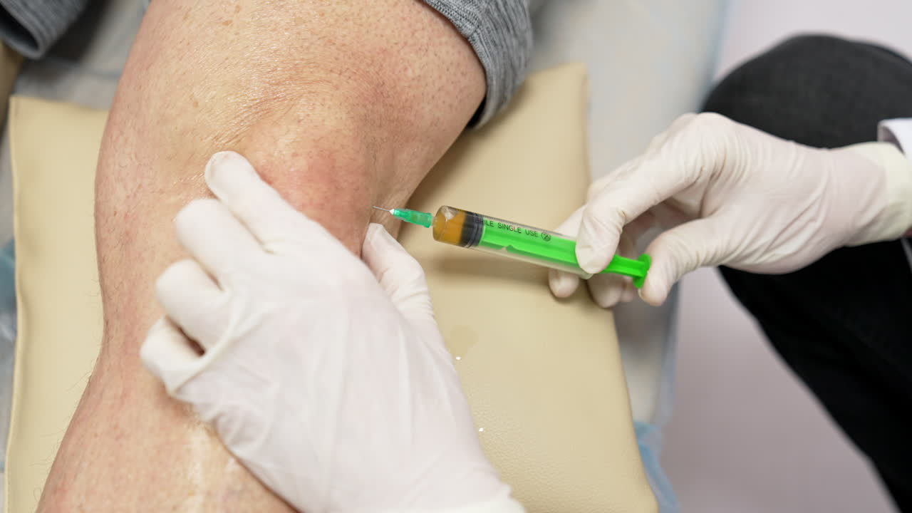 Medic inputs plasma into the patient's knee. Close up. PRP therapy for trauma treatment.