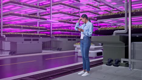 mujer mirando un teléfono inteligente en una granja vertical