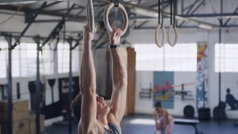 fit man using gymnastic rings for pull ups