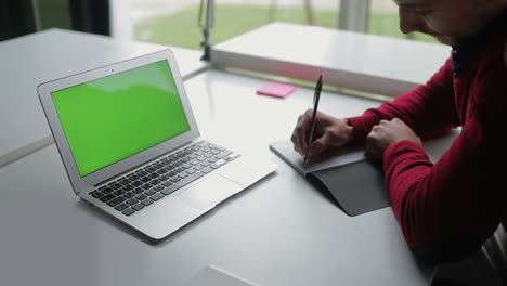 young bearded man making notes in notepad.