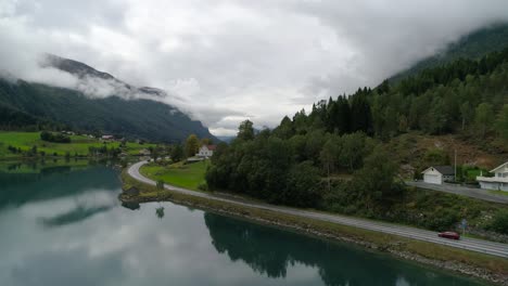 Toma-Aérea-De-La-Plataforma-Rodante-De-Un-Automóvil-Conduciendo-A-Través-Del-Hermoso-Paisaje-Junto-Al-Fiordo-Svortesvada-En-Stryn