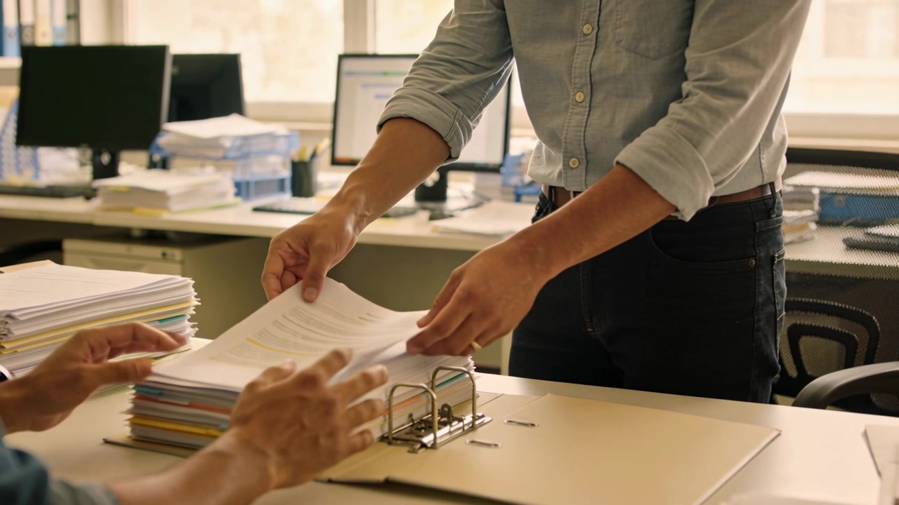 Extending stack, standing worker rolled sleeves handing sheets for filing at office, fitting binder
