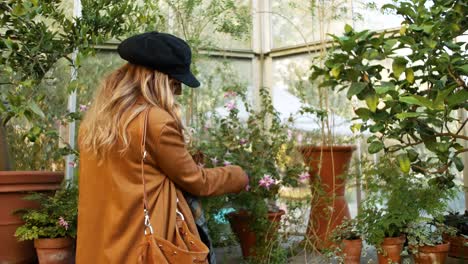 woman in a glass house touches a plant and does not like it