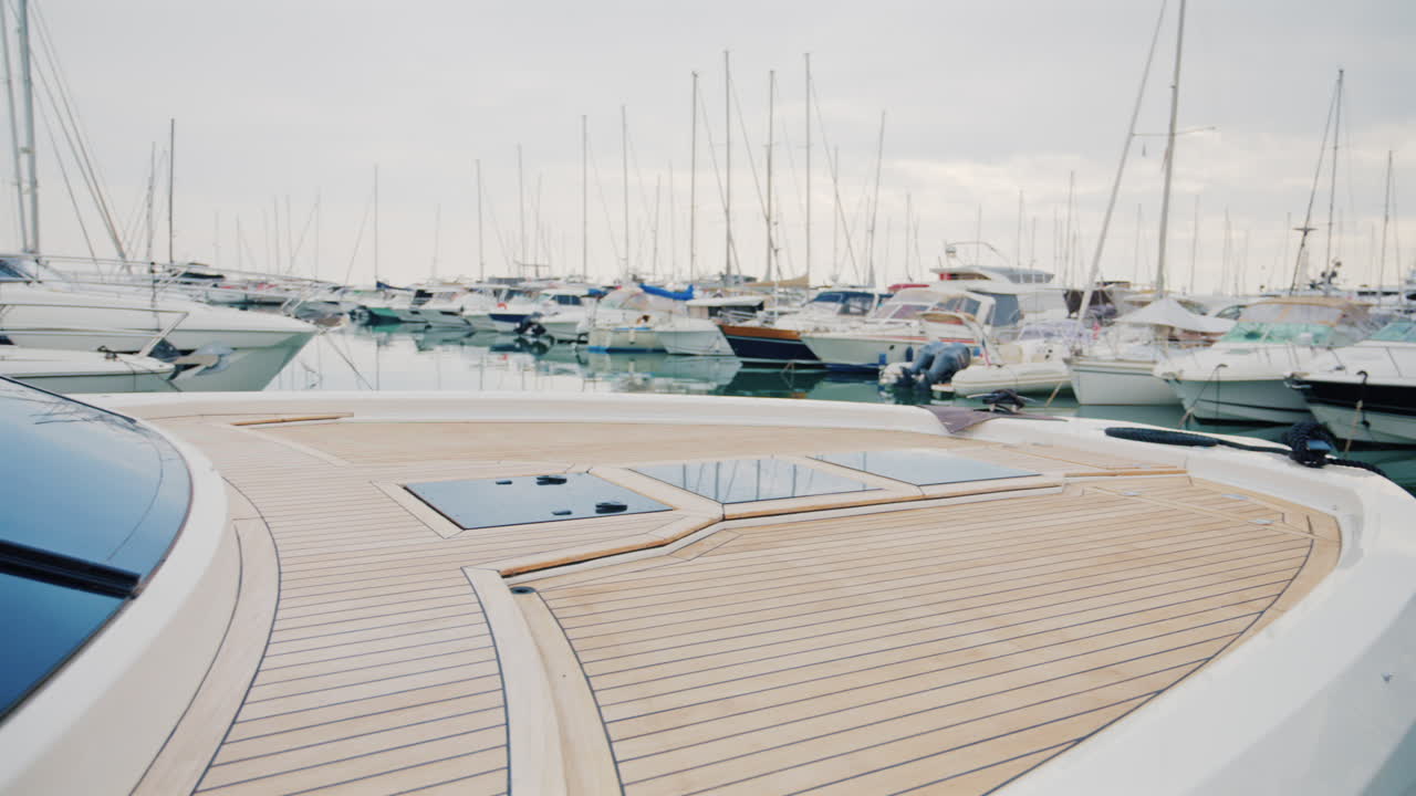 Das Deck einer Luxusyacht mit Blick auf einen friedlichen Yachthafen voller Segelboote und Motoryachten im sanften Tageslicht
