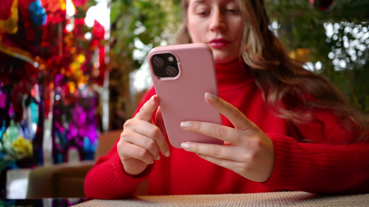 Woman in red sweater working on mobile phone at a restaurant