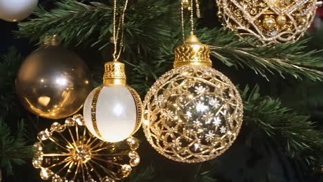 a christmas tree with a red and gold ornament hanging from it. the gold ornament is larger than the red one