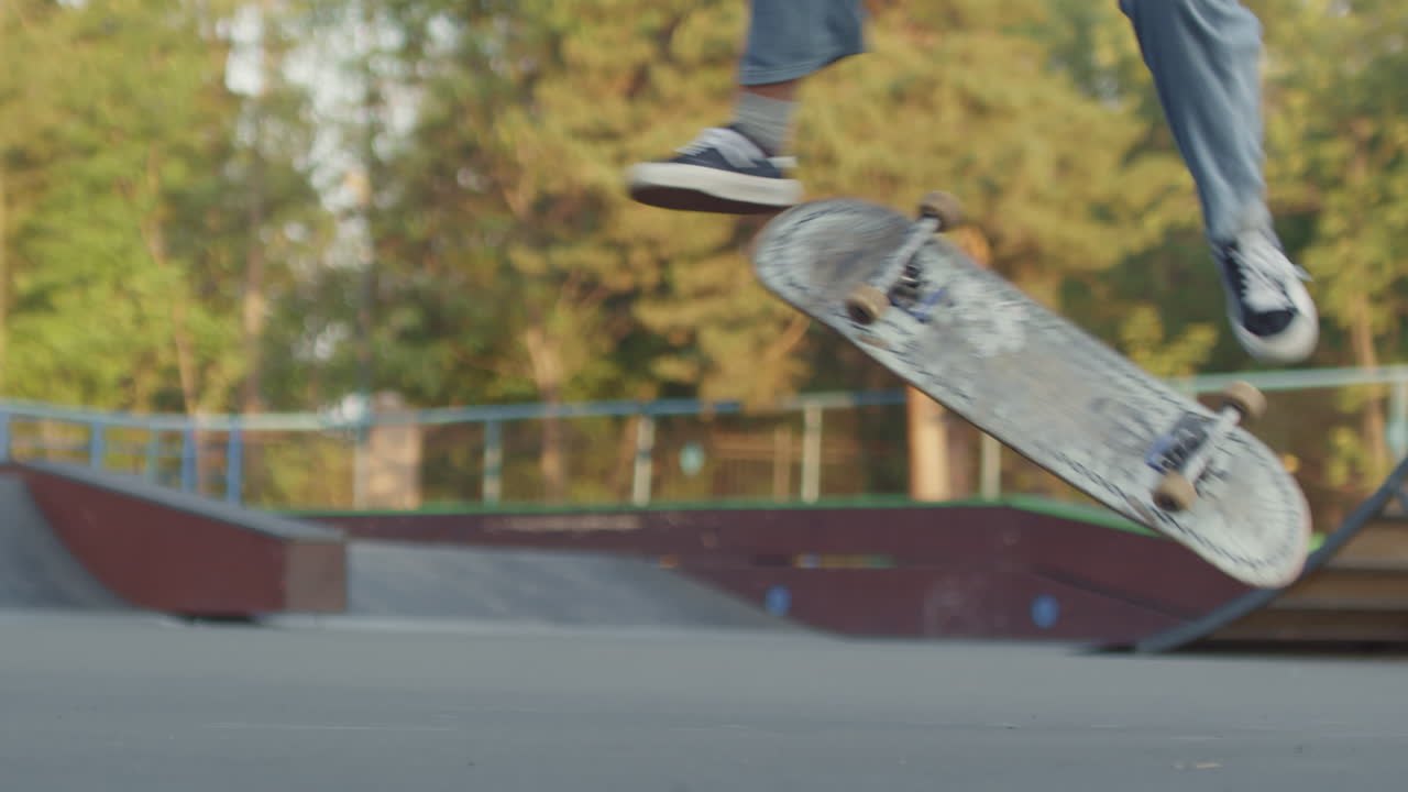 Low-Section of Teenager Doing Kickflip on Skateboard