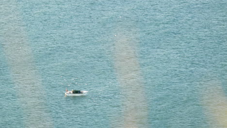 Mann-Beim-Bootfahren-Im-Sonnenaufgang-Mit-Fliegenden-Vögeln-Im-Hintergrund-Am-Strand-Von-Nazare-In-Portugal---Statische-Aufnahme