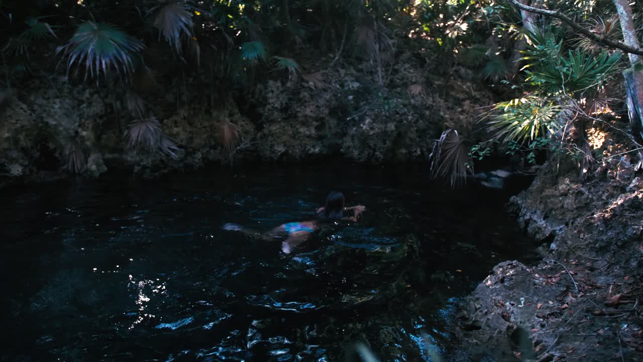 Women swim in the natural pond peeping  handheld