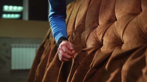 close-up view of a person repairing a tufted brown couch