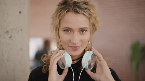 retrato de una hermosa joven mujer rubia estudiante escuchando música quita los auriculares sonriendo disfrutando de actividades de ocio entretenimiento