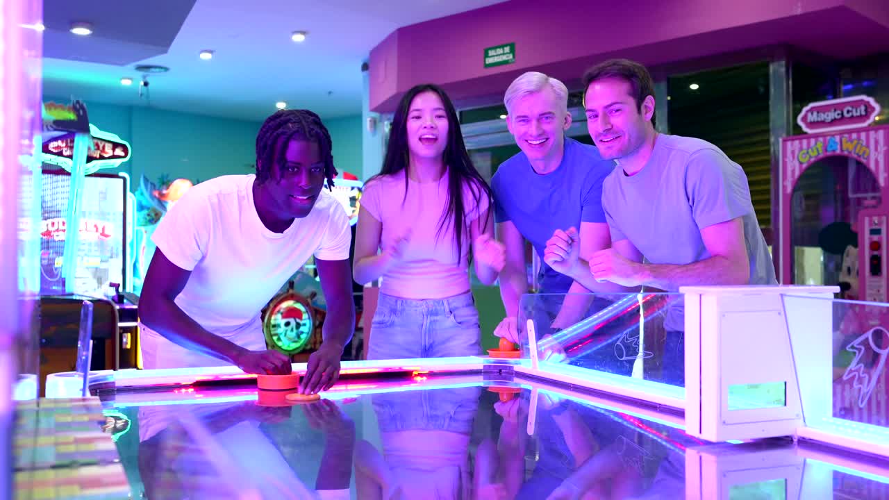 Group of friends playing air hockey in an arcade