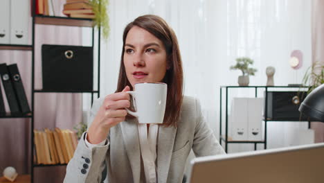 mujer de negocios bebiendo una taza de café caliente sentada en la mesa en el lugar de trabajo de la oficina relajándose tomando un descanso