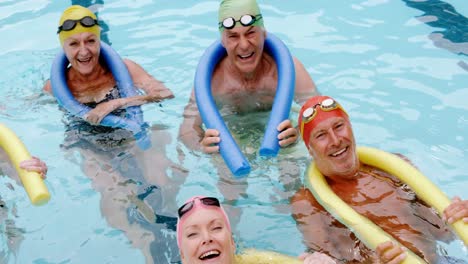 Portrait-of-senior-citizens-swimming-with-inflatable-tube