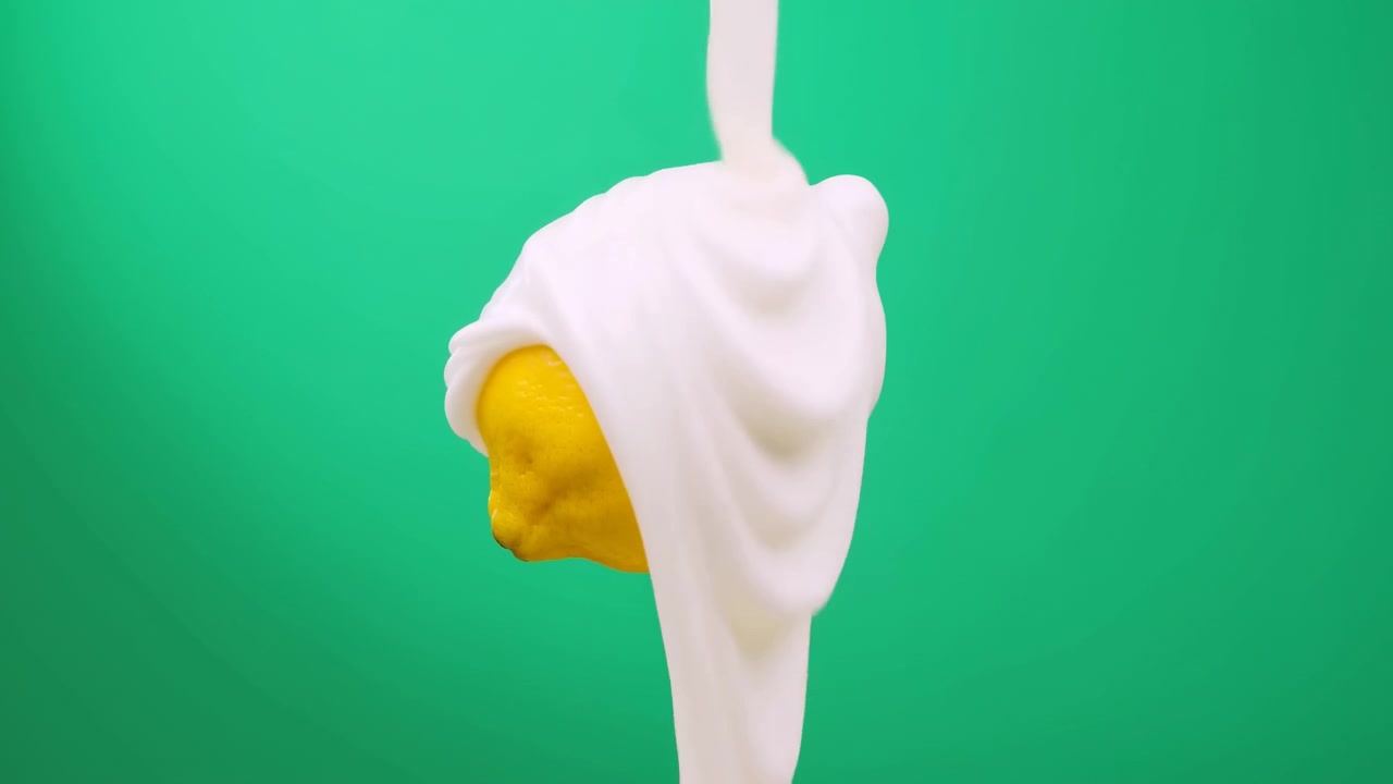 Yellow Lemon On Stick Drenched In Creamy White Swirl Against Green Backdrop, Closeup Of Glossy Citrus Texture
