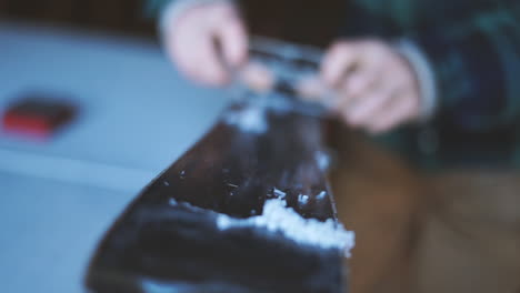slow motion shot of a person scraping wax off a ski after ironing