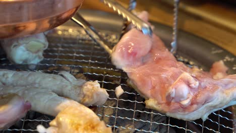asar a la parrilla y voltear la barbacoa de pollo coreana usando pinzas sobre carbón en la ciudad de chuncheon, gangwon en corea del sur
