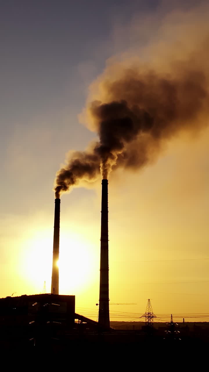 Black factory background. Metallurgical plant with two pipes in the evening. Dirty emissions pouring out of pipes at sunset. Vertical video