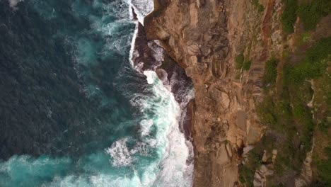 ocean waves crashing and hitting against cliff and rocks bird eye view aerial drone shot