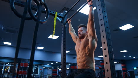 strong man doing pull ups in gym. male athlete with fit torso doing pull ups indoor