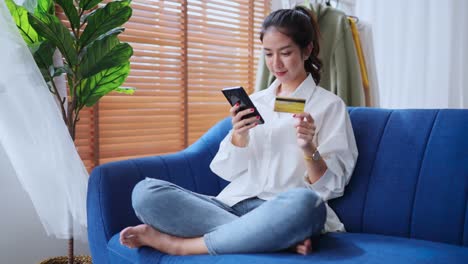 smart casual asian female close up hand using smartphone and credit card online payment internet transaction shopping online at home,beautiful asia woman smiling pleasure while shopping online at home