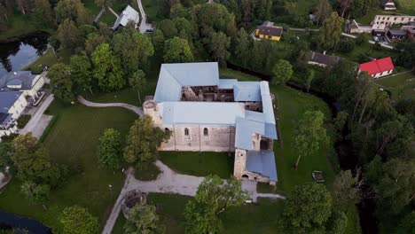 Drone footage showcases the historic Padise Cistercian Monastery ruins in Harju County Estonia where medieval stone walls and arched windows stand surrounded by open fields and peaceful countryside