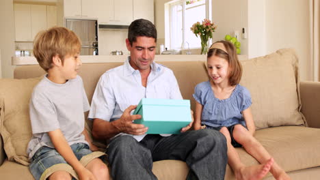 cute children giving their father presents on the couch