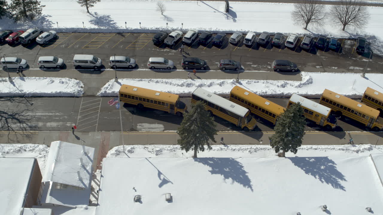 Aerial of School Buses at Snowy Elementary School Parking Lot During Winter