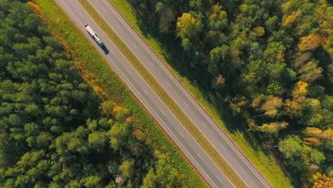 highway road between trees. aerial view of truck driving at road at forest