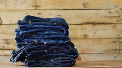 close up of folded jeans with different shades on wooden background with copy space