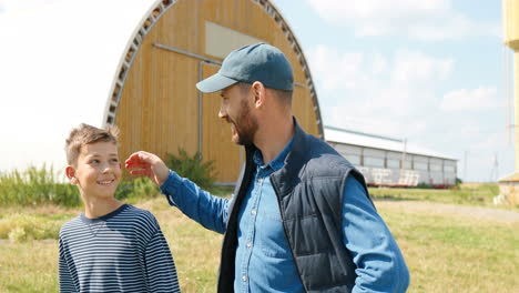 caucasian man with his teen boy talking and walking outside the stable in the field