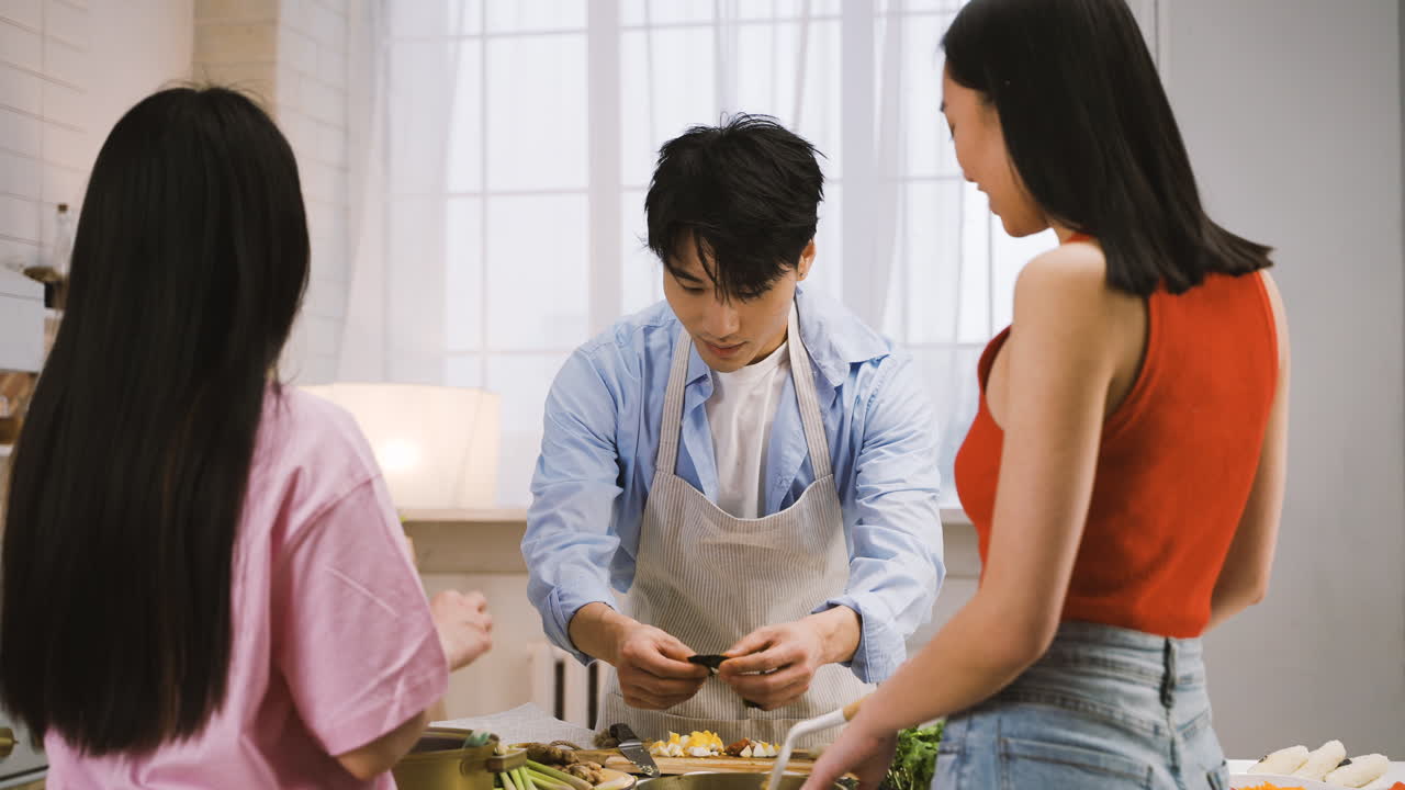 두 명의 일본 여성과 남성이 부엌에서 이야기하면서 일본 음식을 요리하고 있습니다.