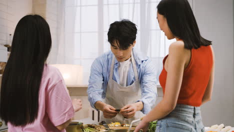 두 명의 일본 여성과 남성이 부엌에서 이야기하면서 일본 음식을 요리하고 있습니다.