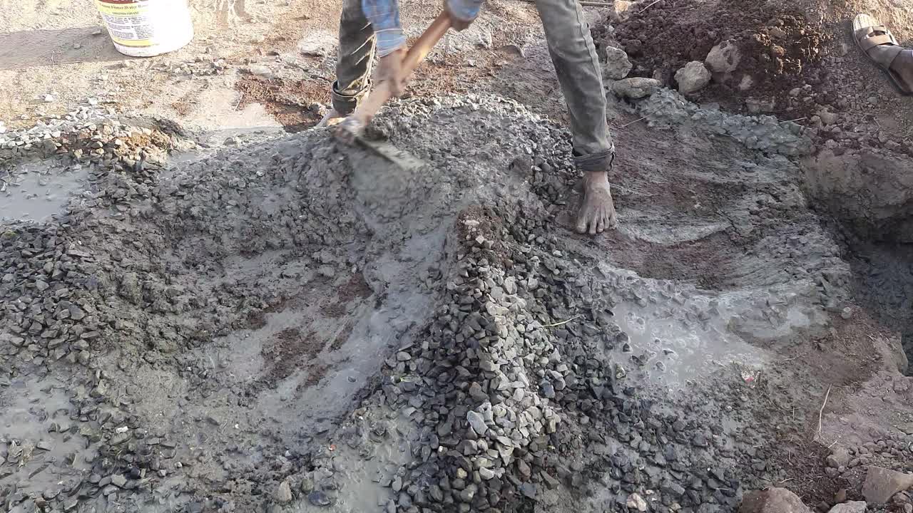 Labor pouring concrete into steel box for foundation pillar in process of house building at construction site in India