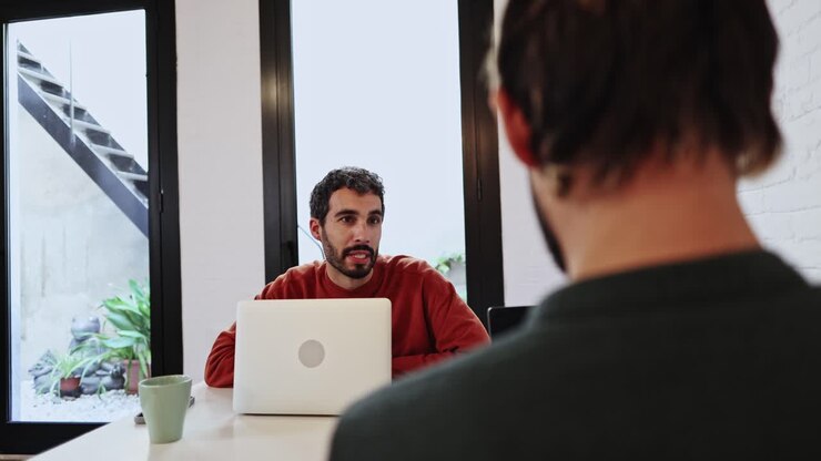Smiling Man Talking to Colleague During an Office Meeting