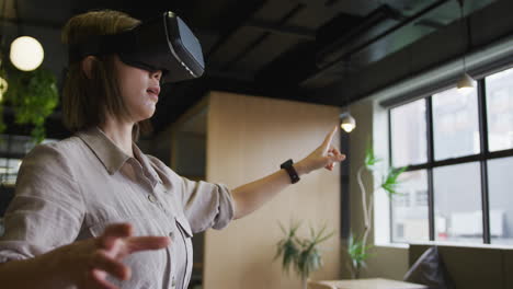 una mujer de negocios asiática de pie usando vr googles en una oficina moderna