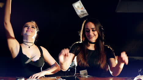 two young female laughing and throwing american dollars in the air. slow motion. criminal business