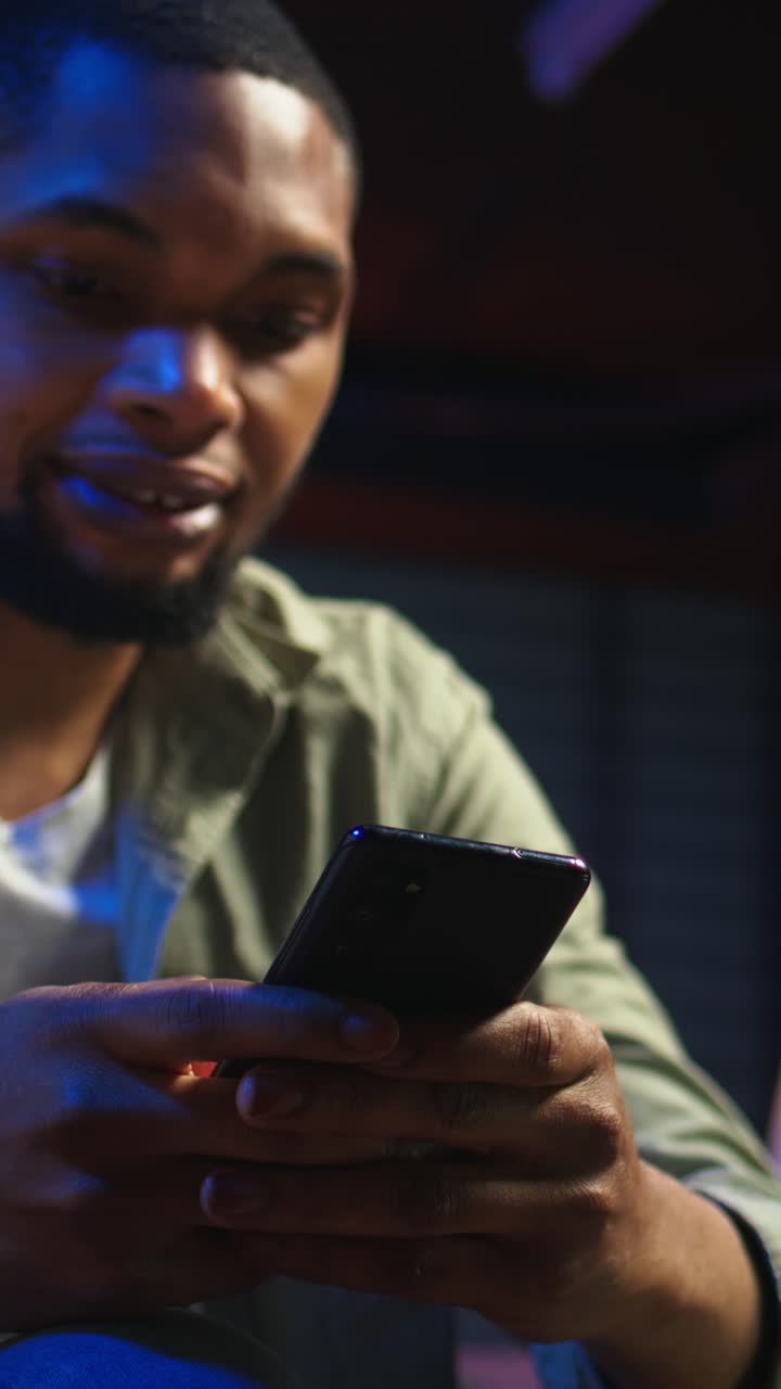 Vertical Video Casual african american man browsing on his smartphone in a comfortable space