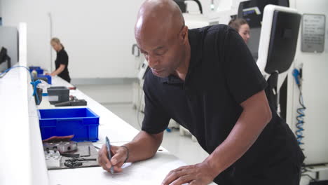 ingeniero tomando notas sobre el dibujo técnico en la fábrica