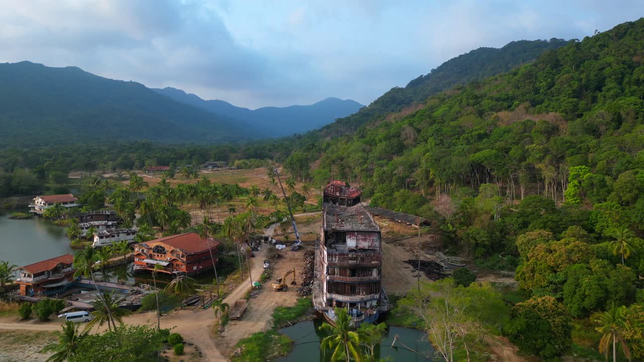 Abandoned resort showing decaying buildings, surrounded by palm trees and a lake, in Koh Chang, Thailand. Nice aerial view flight ascending drone