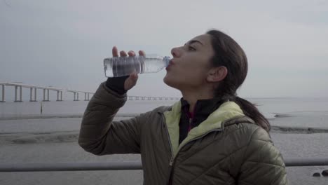 smiling hindu woman drinking water during workout