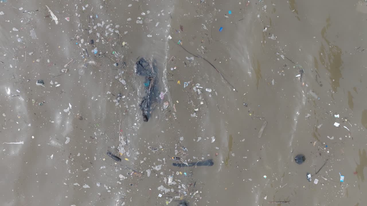 인도네시아 발리에서 떠다니는 쓰레기와 잔해로 가득 찬 오염된 바다의 느린 움직임, 낮은 고도, 위에서 아래로 드론